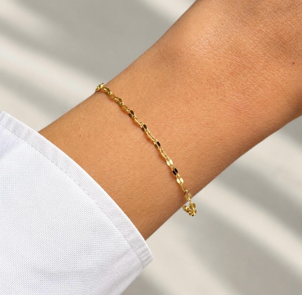 Delicate 14K gold plated faceted chain bracelet worn on wrist with white sleeve
