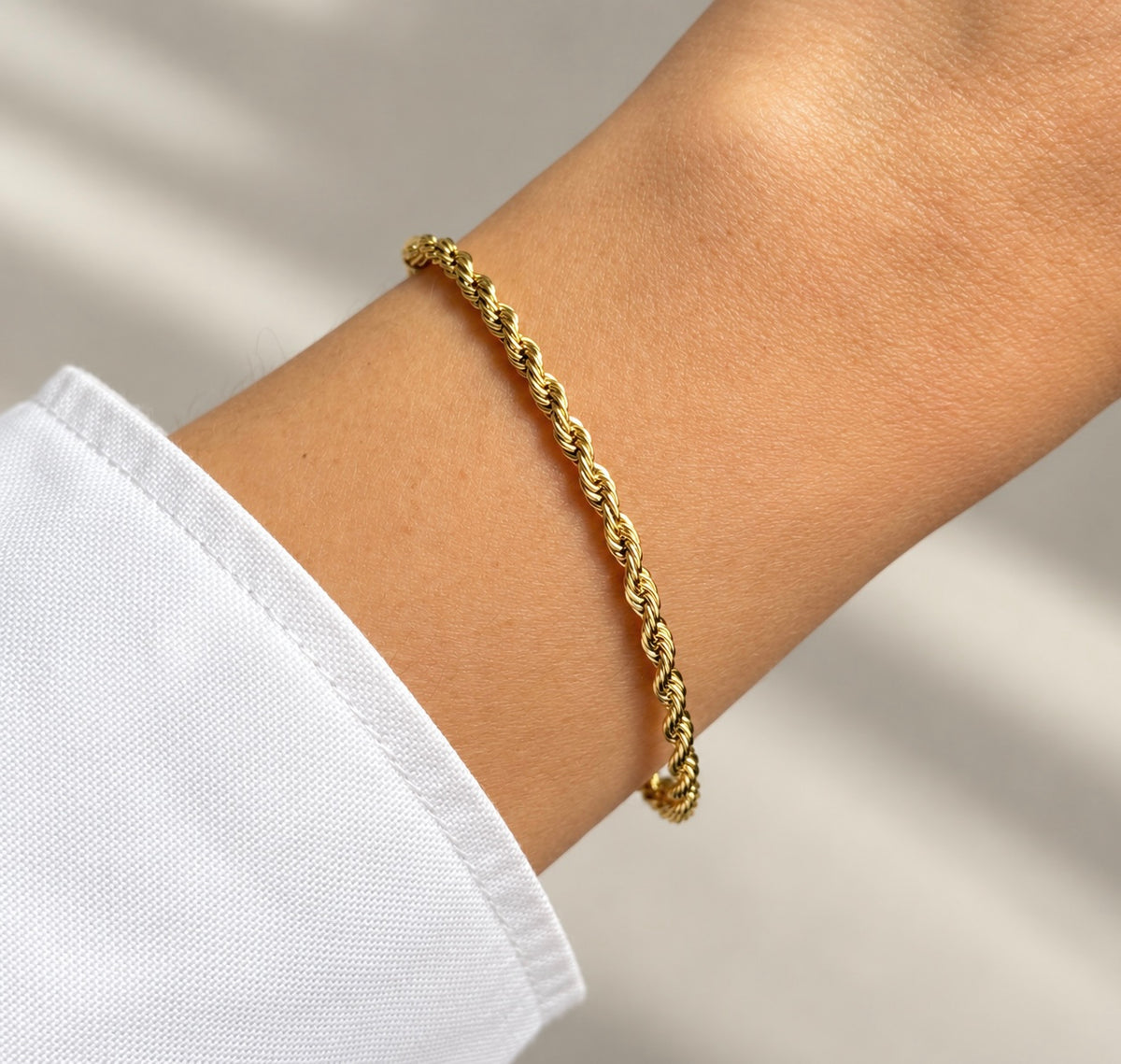 14K gold plated twisted rope chain bracelet worn on wrist, close-up