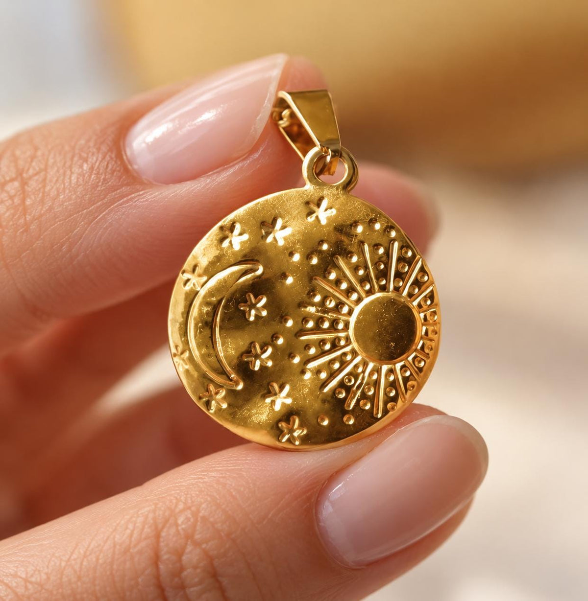 Close-up of round gold plated medallion pendant with raised sun, crescent moon and stars