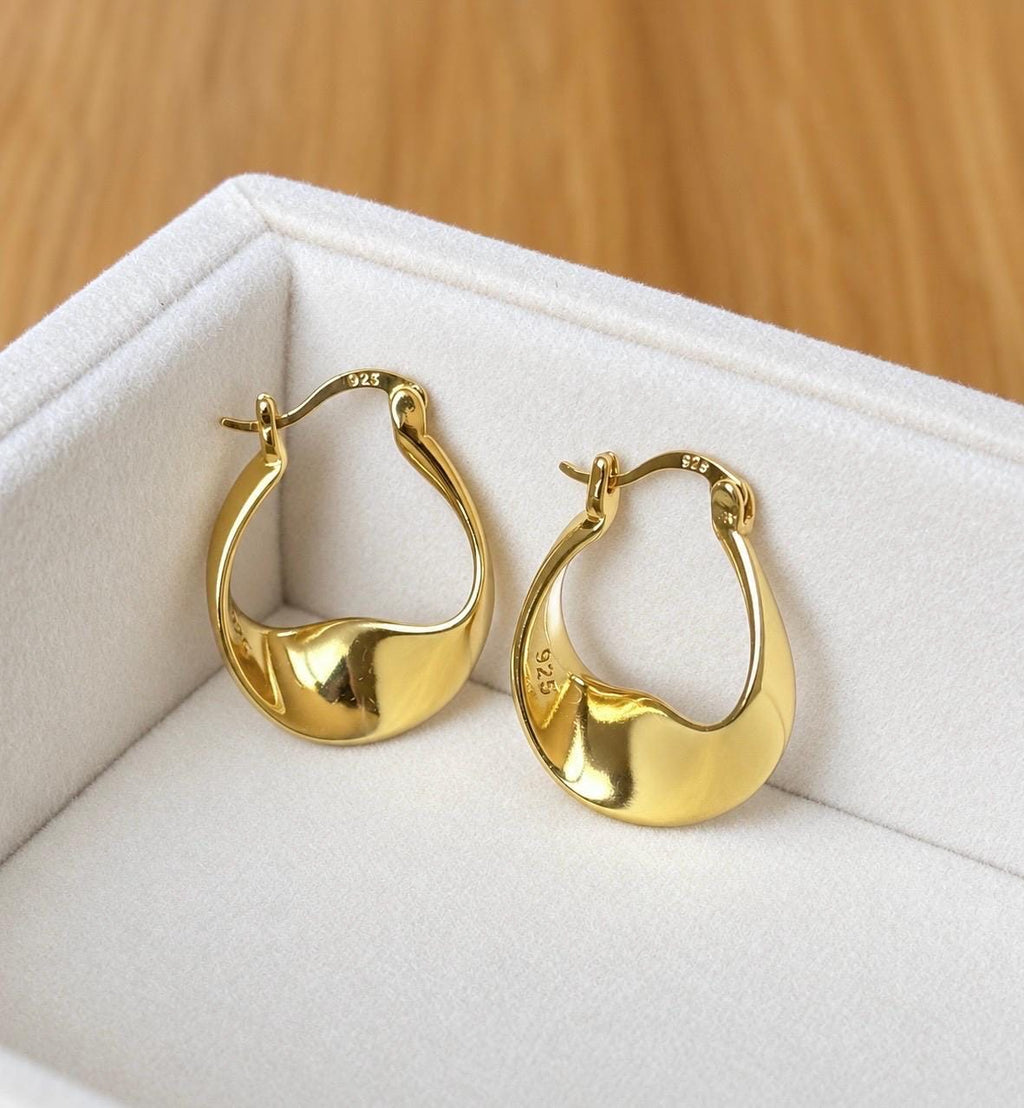 Pair of 18K gold plated 925 sterling silver organic twist hoop earrings displayed on cream velvet