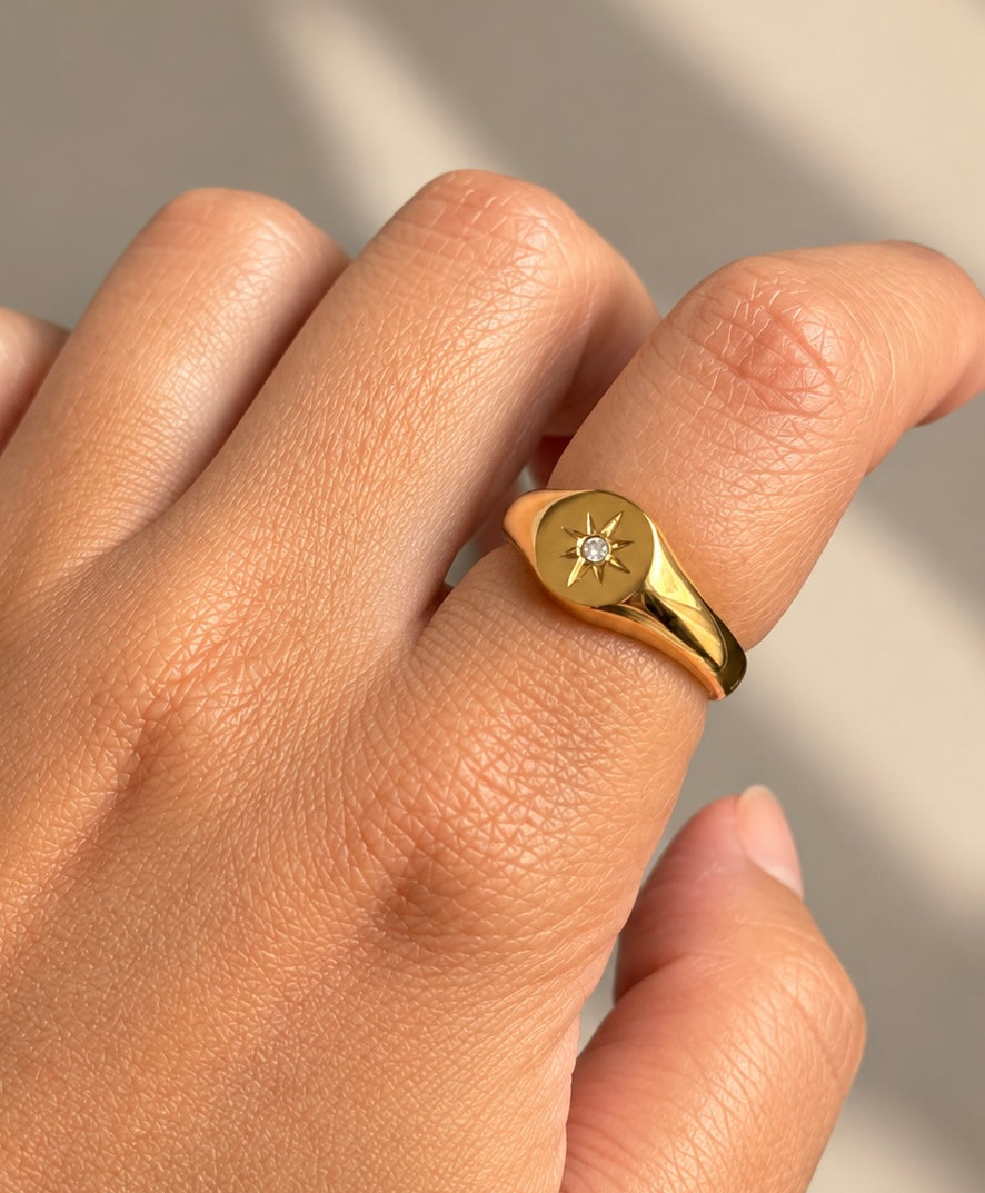 Gold-plated North Star signet ring worn on a finger close up