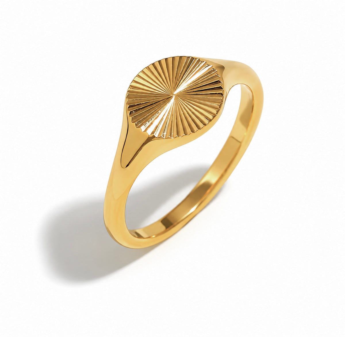 Close up studio view of gold sunburst signet ring with textured circular face