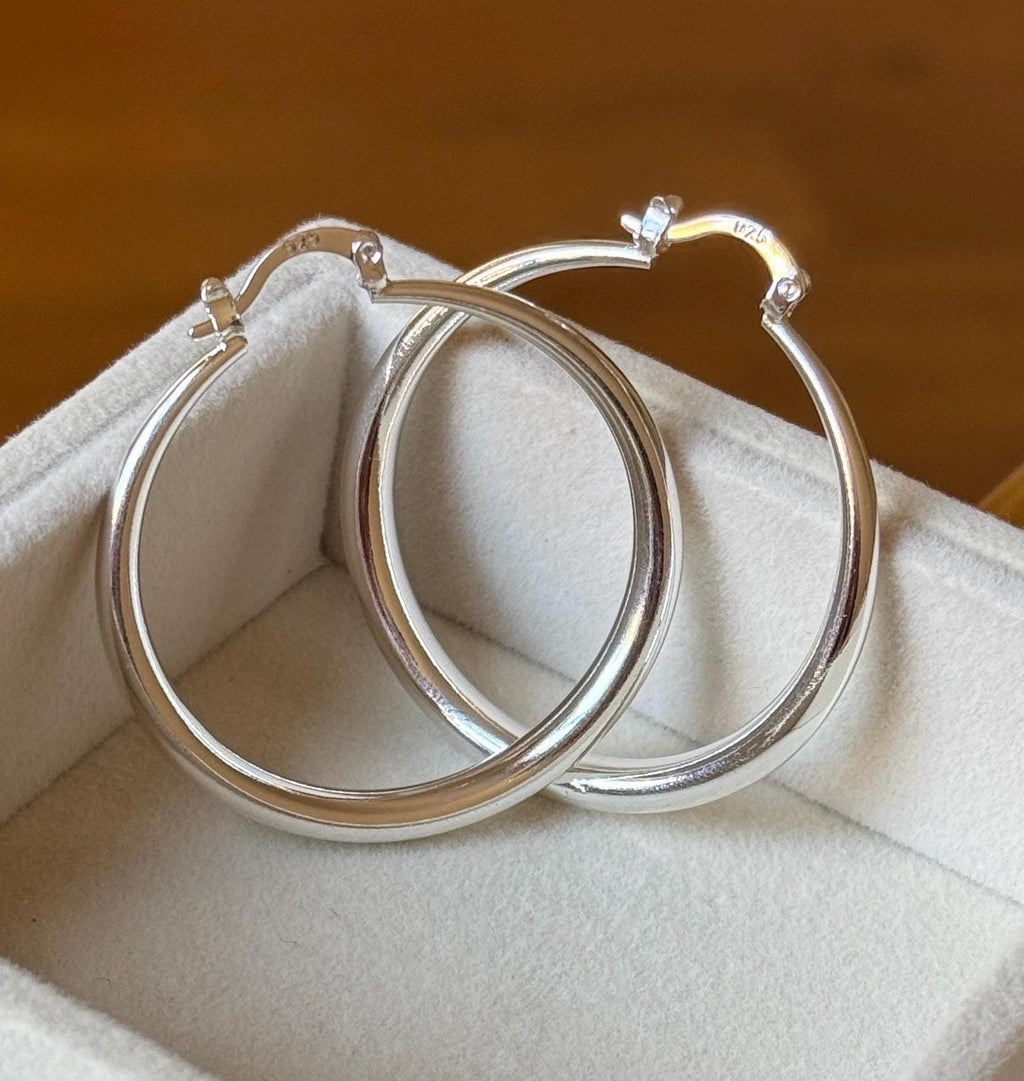 Close-up of overlapping polished sterling silver 40mm hoops