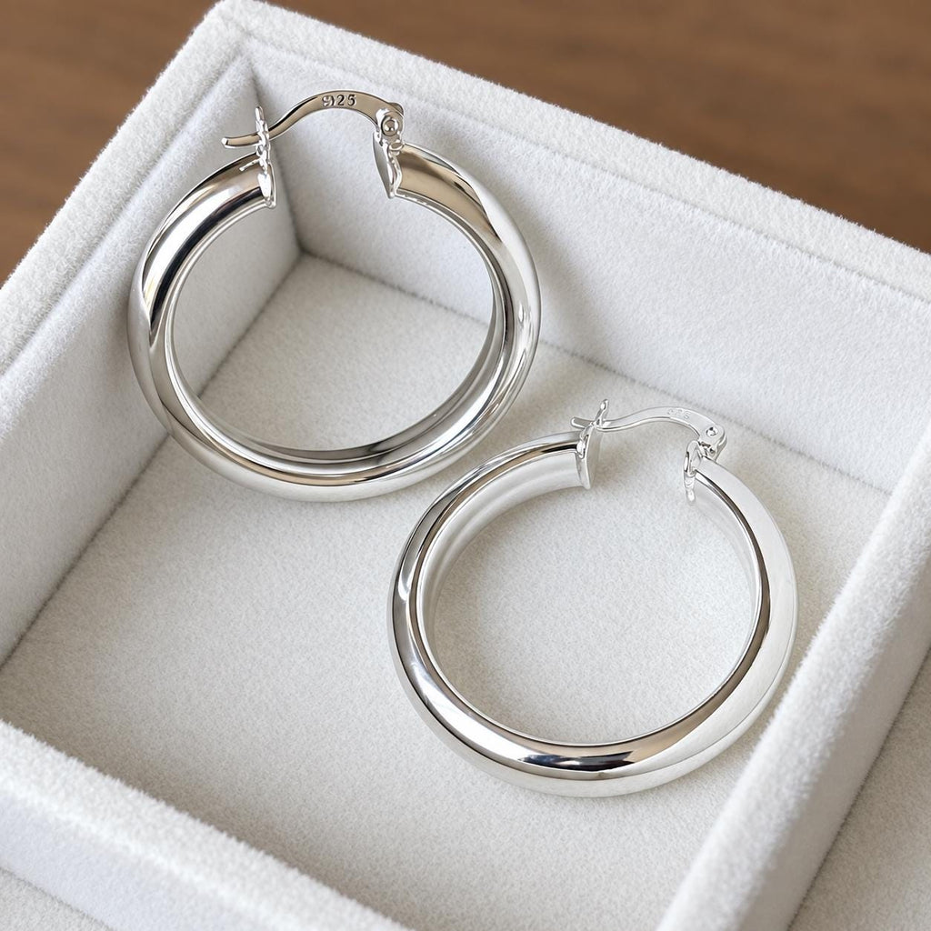 Pair of 35mm polished 925 sterling silver hoop earrings with hinged closures in an ivory velvet jewellery tray
