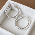 Pair of 35mm polished 925 sterling silver hoop earrings with hinged closures in an ivory velvet jewellery tray