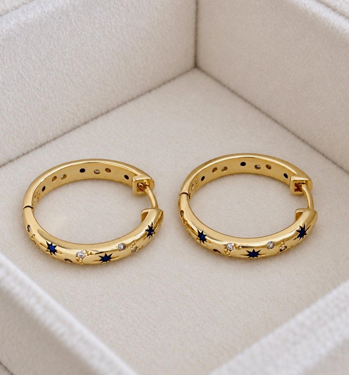 Close-up of gold-plated 925 silver hoop earrings with blue stars and sparkling moon details