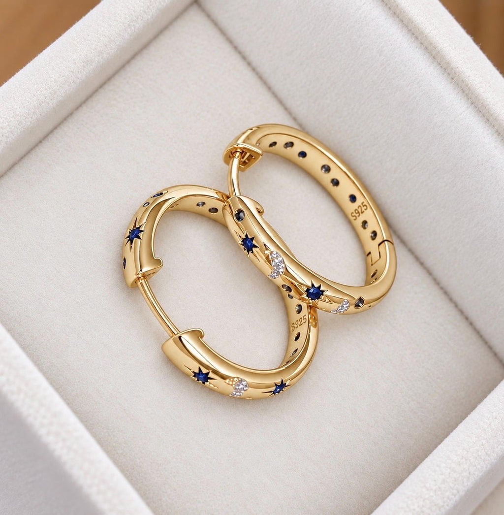 Open gold-plated sterling silver celestial hoop earrings with blue stars and crescent moon pattern