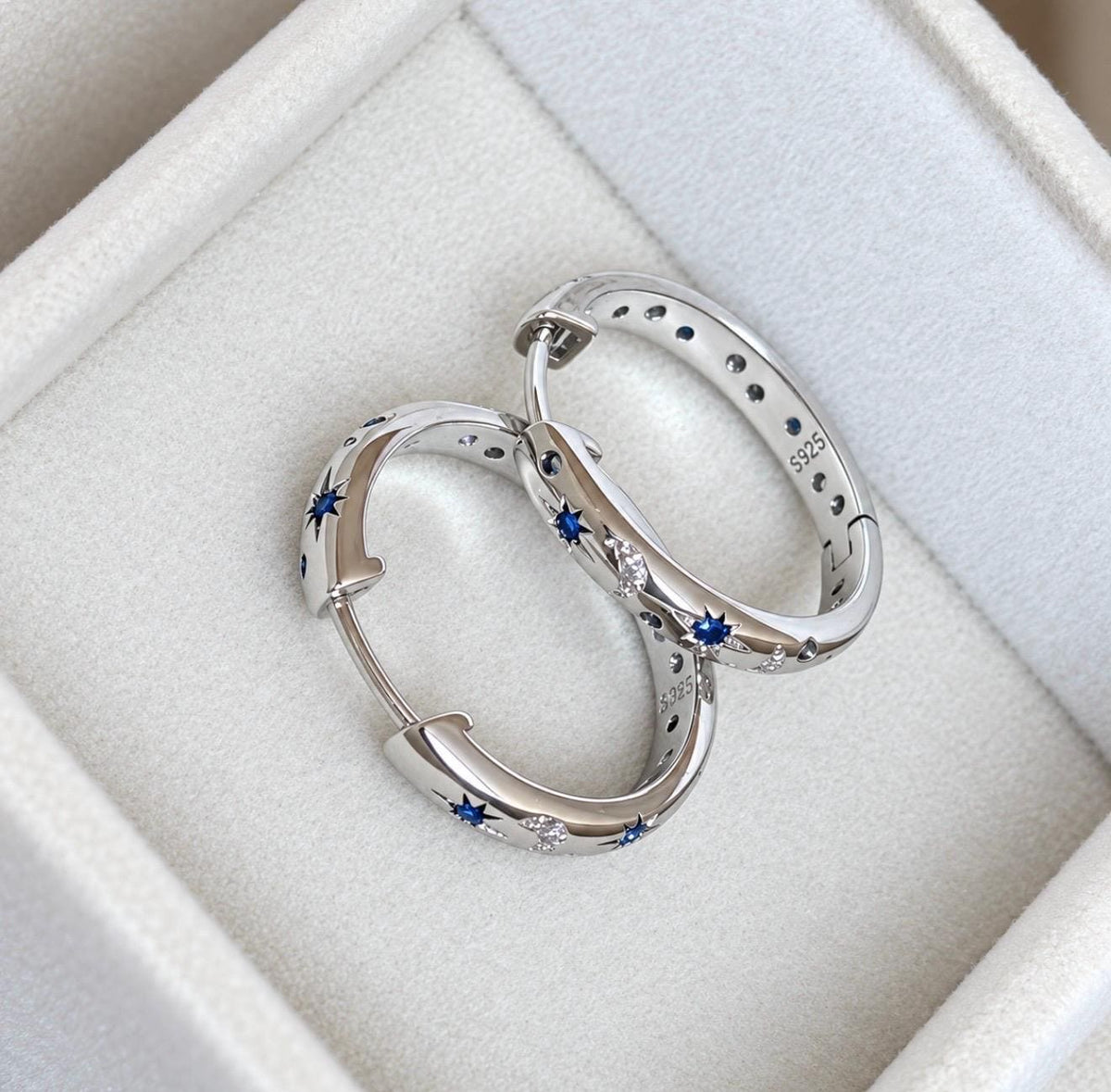 Open sterling silver celestial hoop earrings with blue star and crescent moon pattern