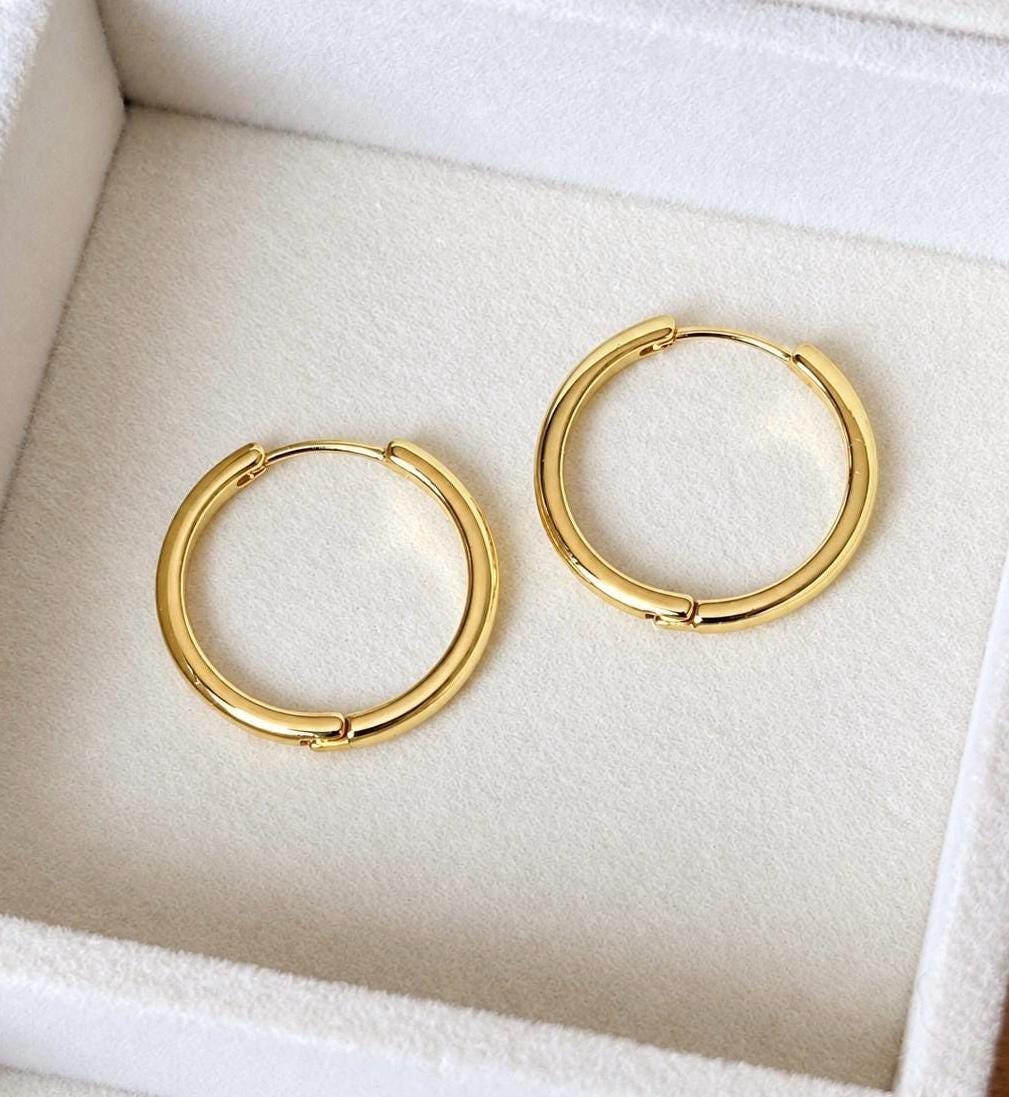 Pair of simple polished gold plated 925 sterling silver hoop earrings on ivory jewellery tray