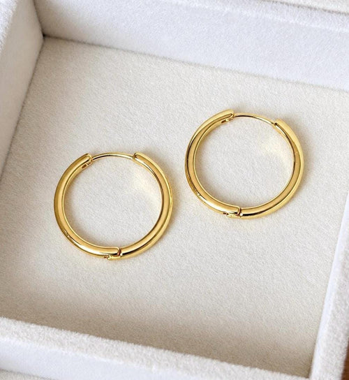 Pair of simple polished gold plated 925 sterling silver hoop earrings on ivory jewellery tray