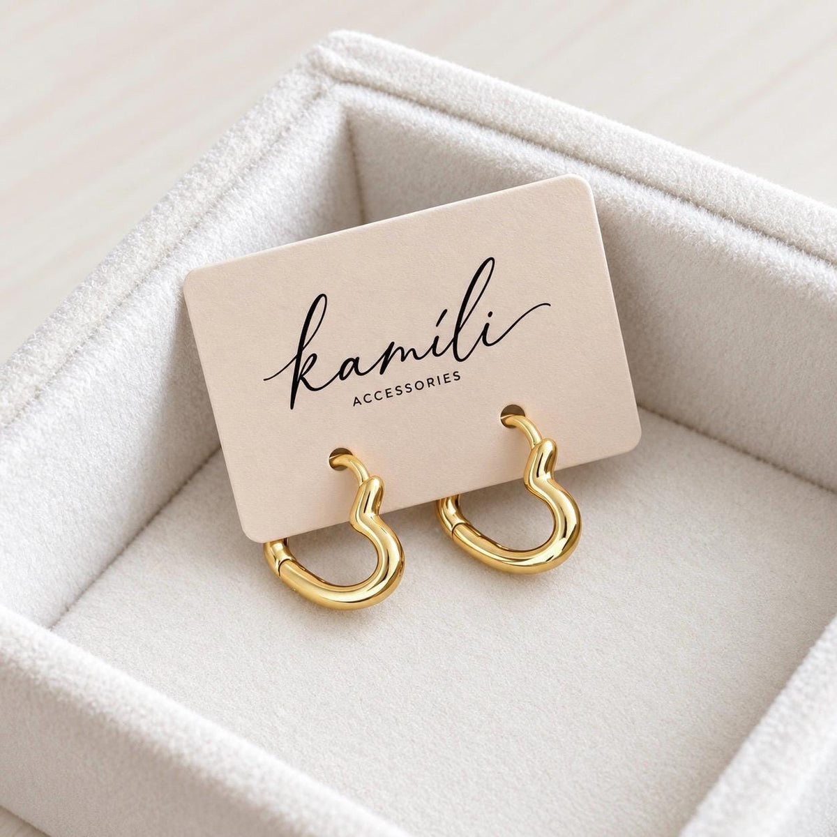 Pair of gold heart hoop earrings on Kamili Accessories branded card in a cream jewellery box