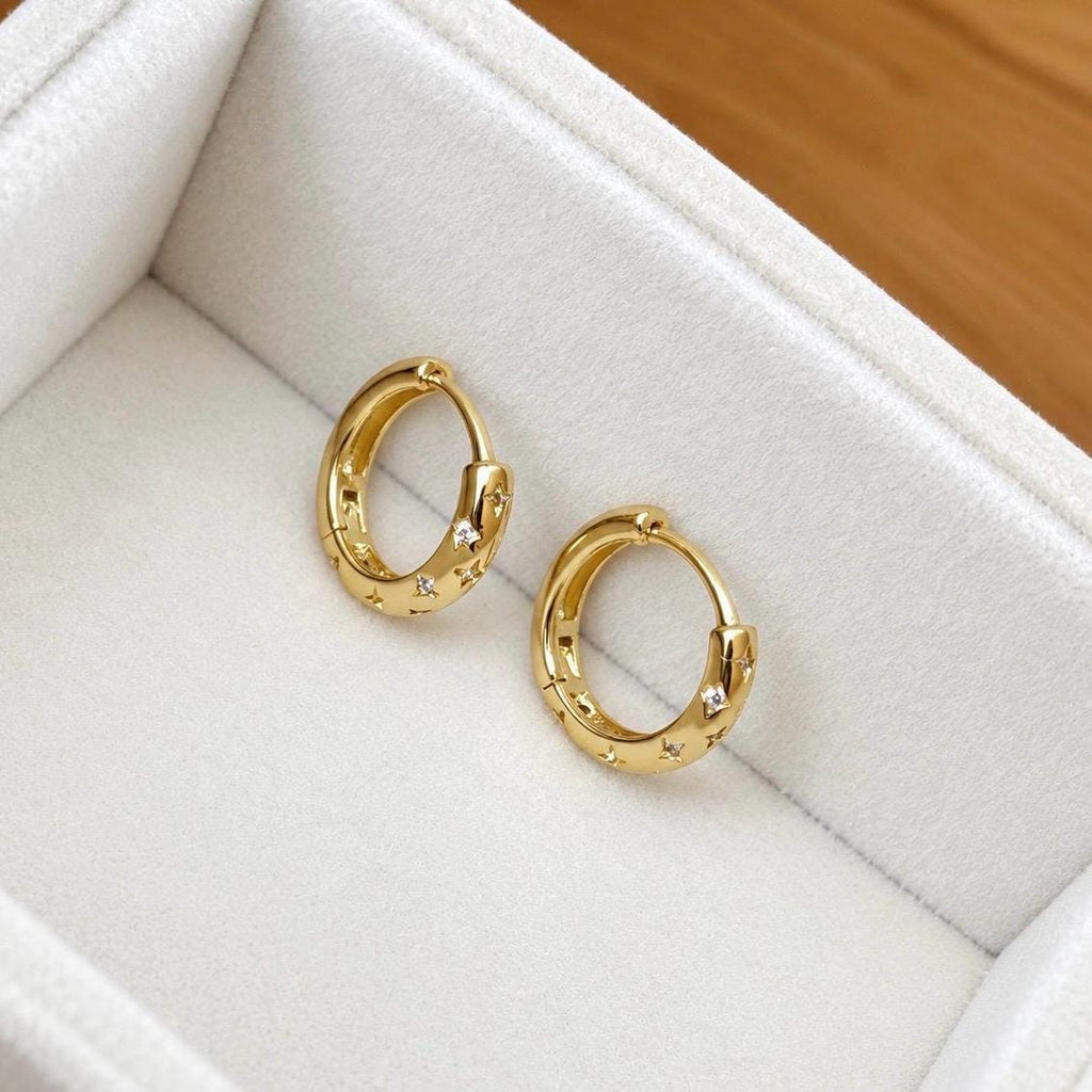 Pair of small gold celestial engraved hoop earrings showing clear CZ star details