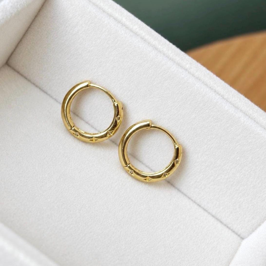 Gold star engraved cubic zirconia hoop earrings viewed from the front