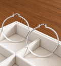 Pair of large 55mm polished 925 sterling silver hoop earrings displayed on cream jewellery tray