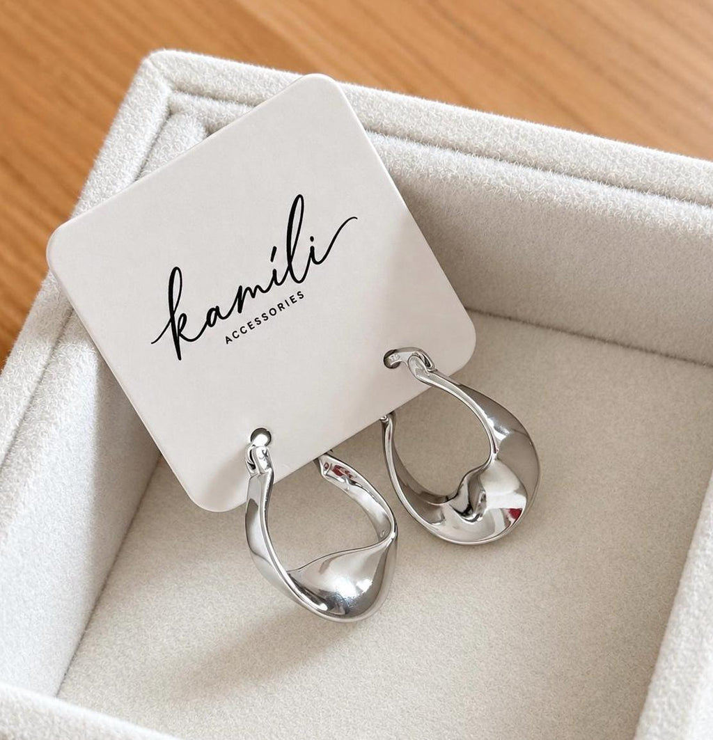 Silver organic twisted hoop earrings displayed on Kamíli Accessories branded card