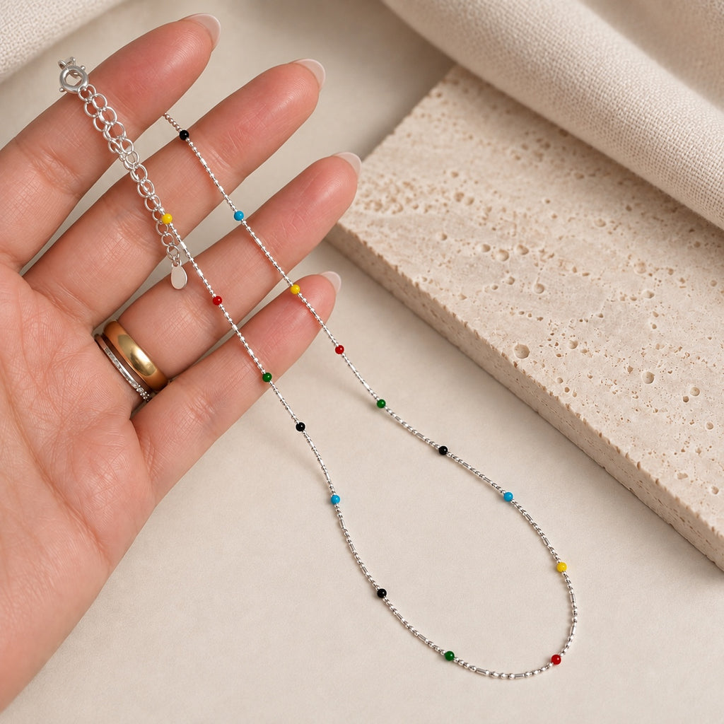 925 sterling silver rainbow beaded necklace with small red blue green yellow and black beads held in hand