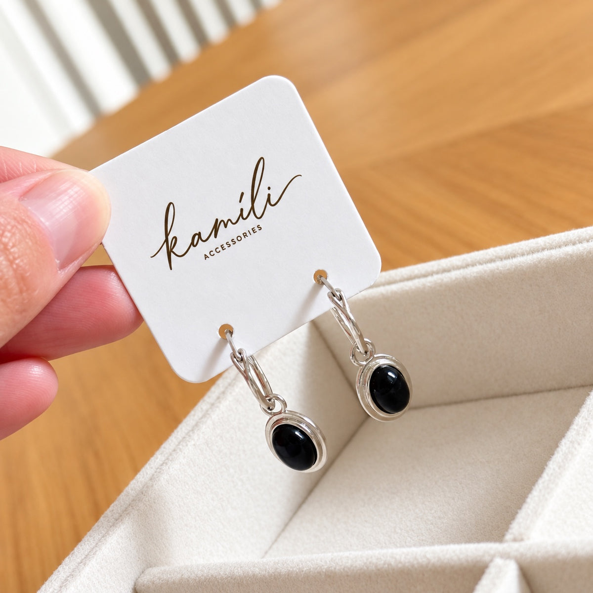 Angled product view of black agate drop earrings on branded card