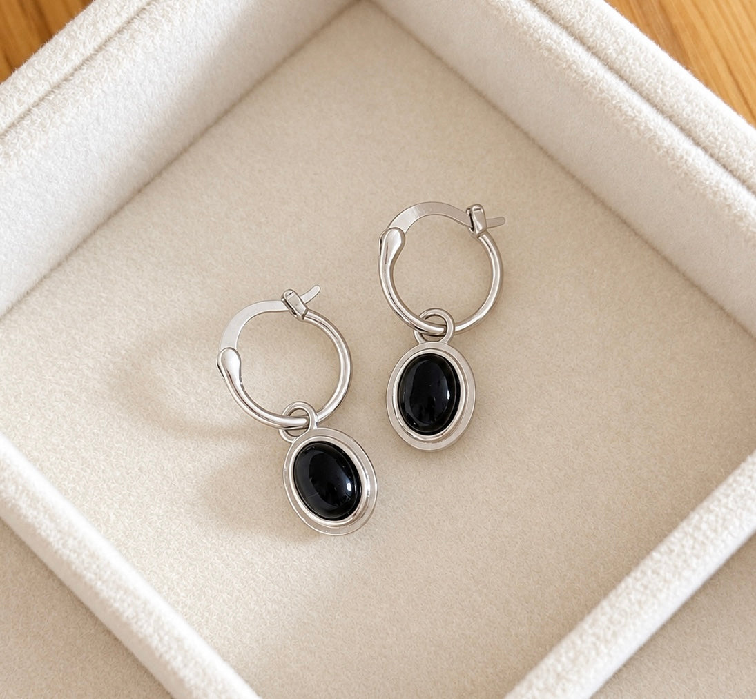 Black agate oval silver dangle earrings laid in a plush ivory jewellery box
