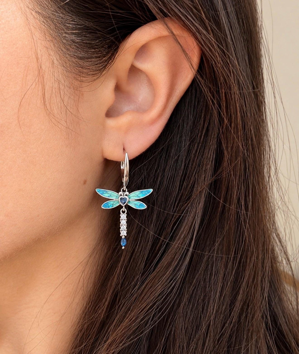Blue turquoise dragonfly drop earring worn on ear showing silver hoop fastening and dangle length