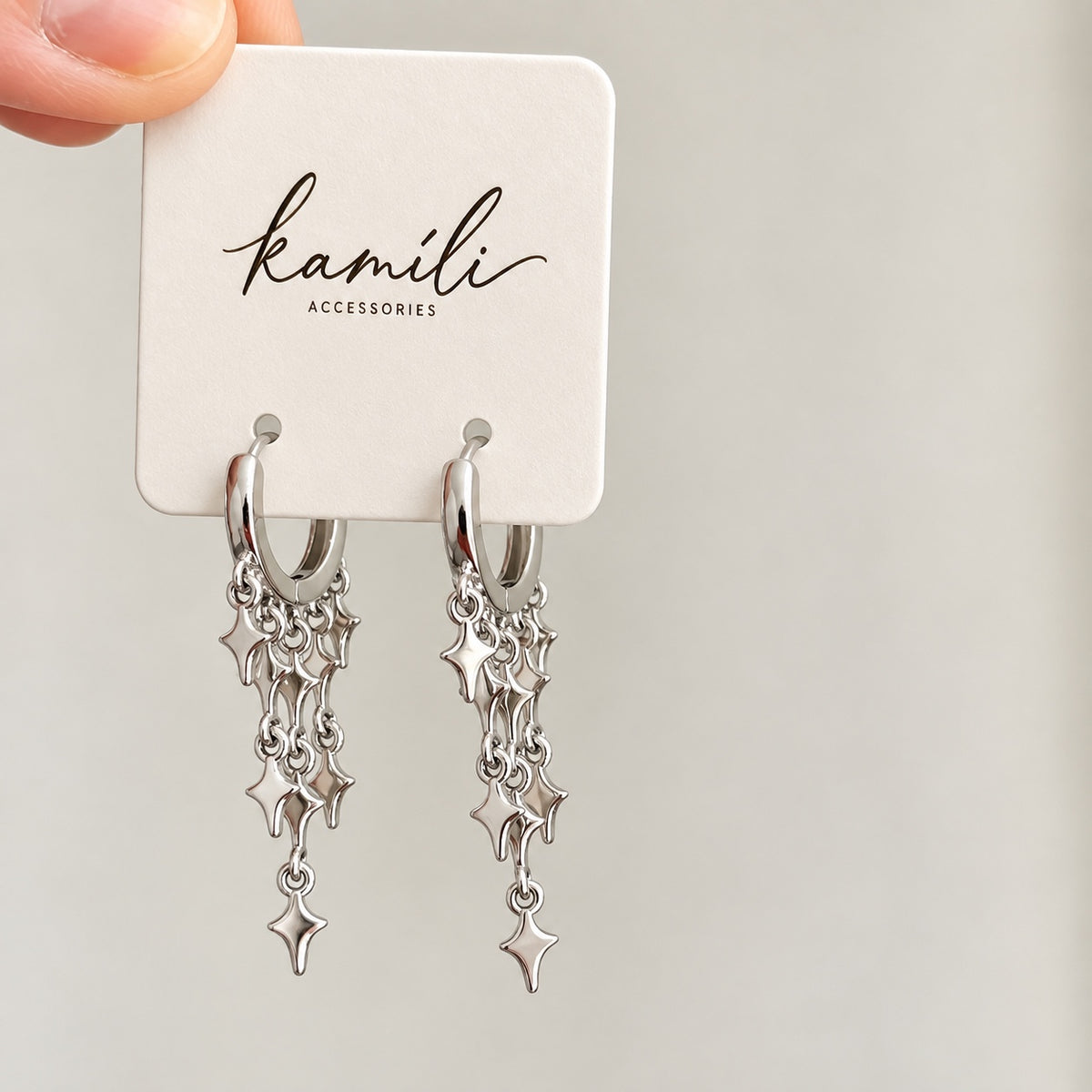 Star charm silver huggie hoops on Kamíli Accessories branded card