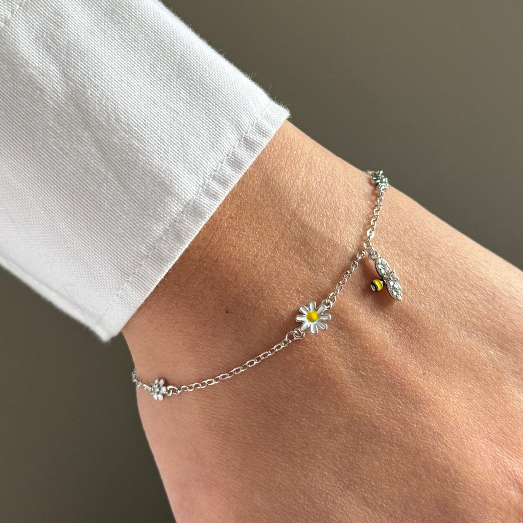Daisy and bee charm bracelet worn on wrist in close-up