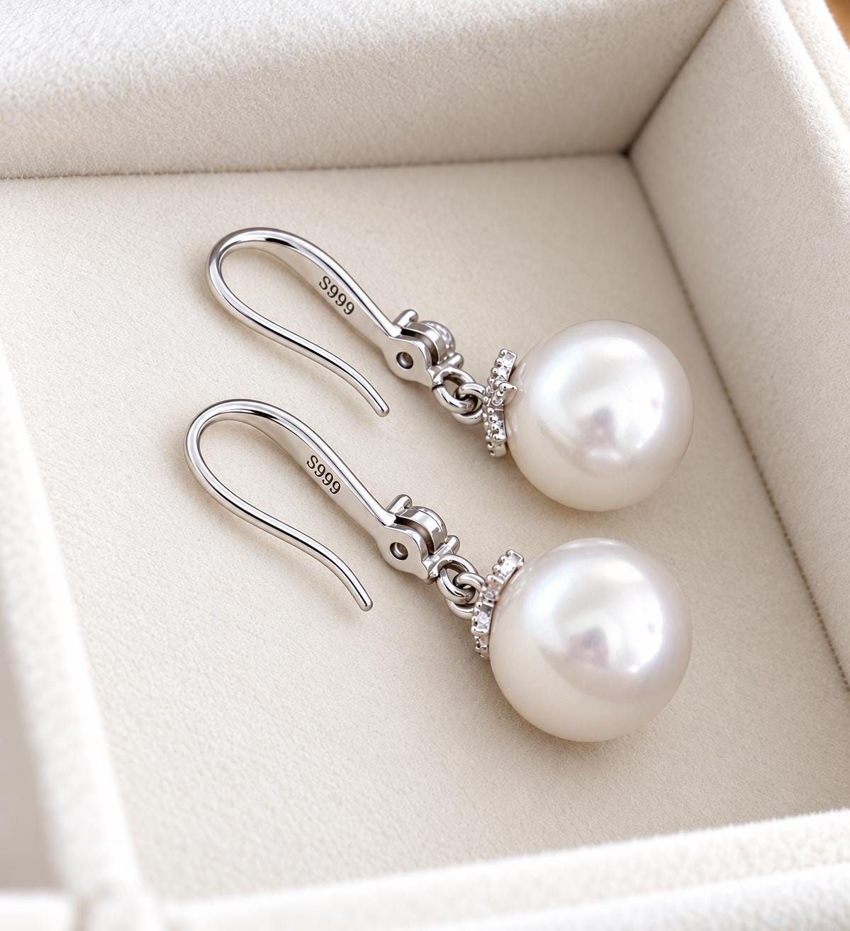 Back detail of fine silver pearl hook earrings with S999 marks visible