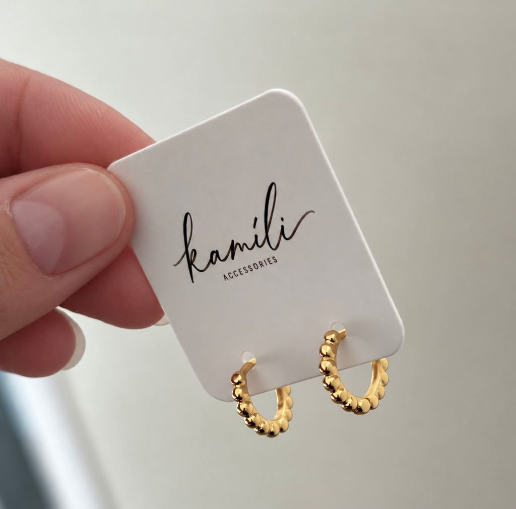 Gold beaded earrings card held in hand