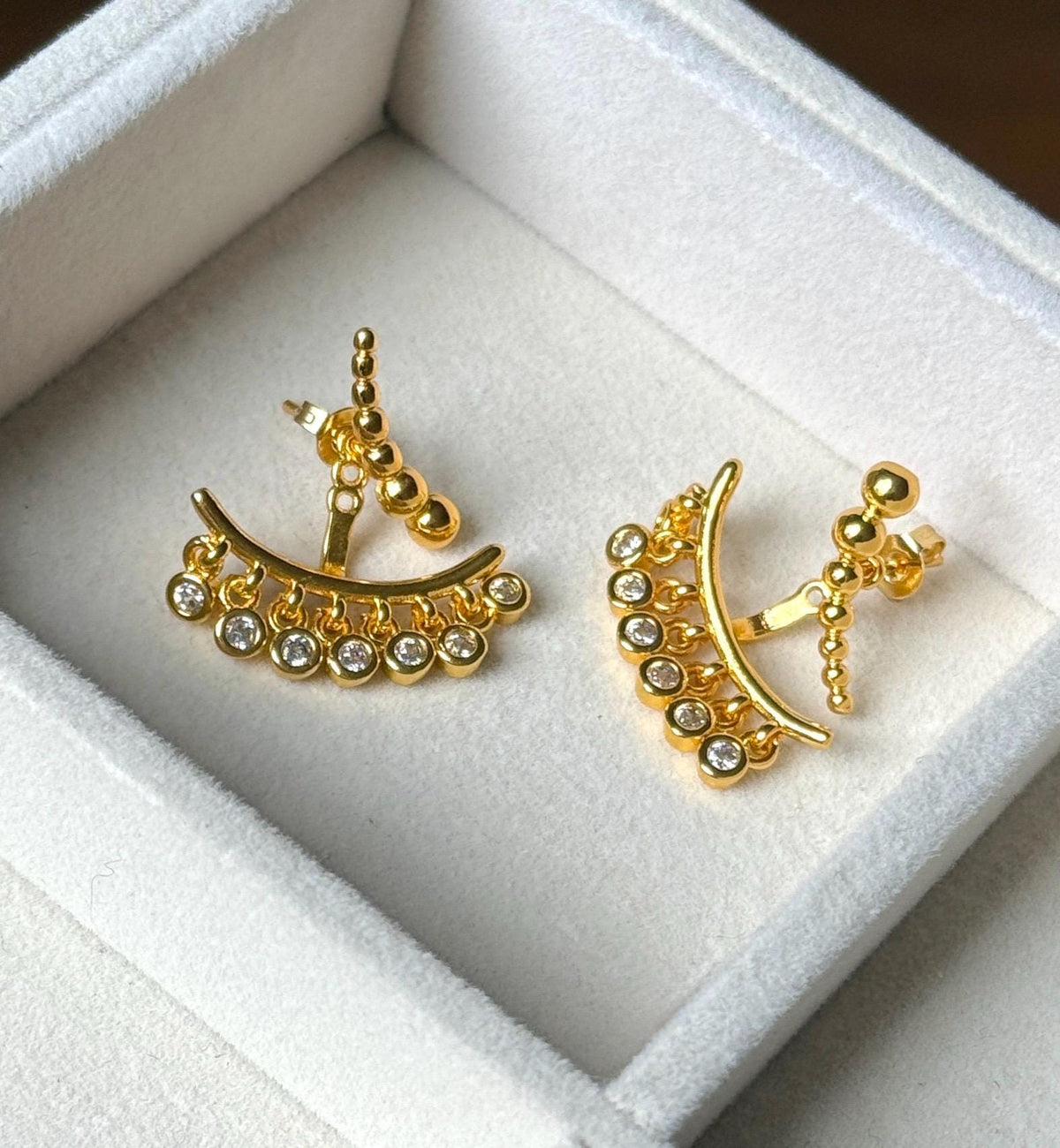 Back and side view of gold plated beaded ear jacket earrings with clear CZ drops