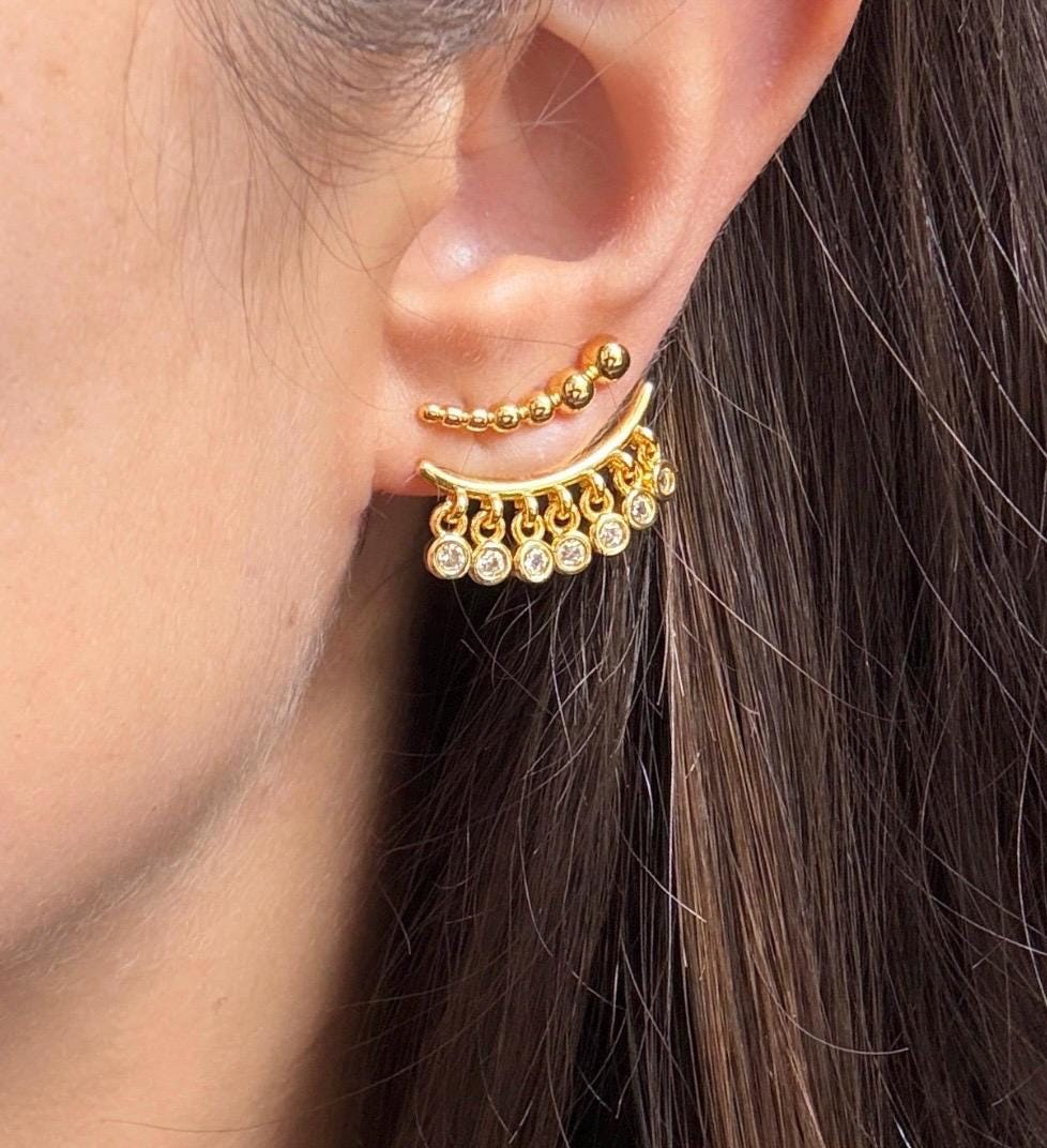 Gold beaded CZ ear jacket earrings on ear, showing the curved row of glittering dangling clear stones