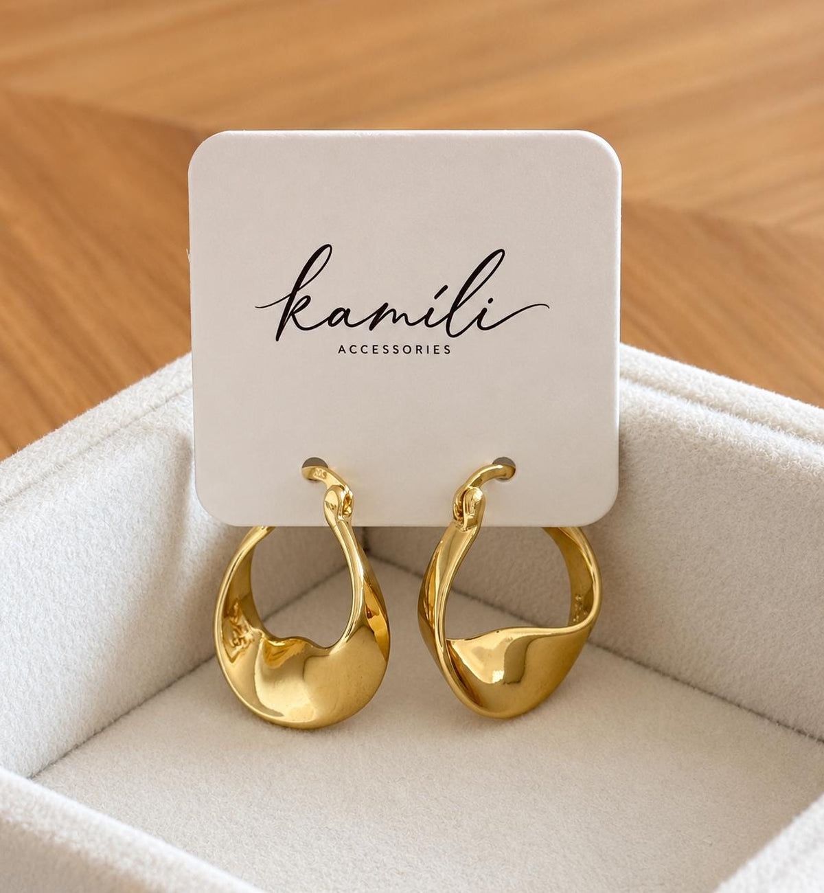 Gold plated sterling silver twist hoops hanging from Kamíli Accessories branded card