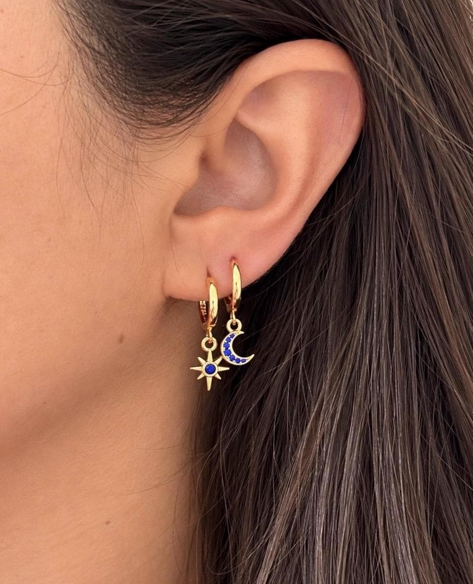 Gold plated silver moon and star huggie earrings worn together on an ear
