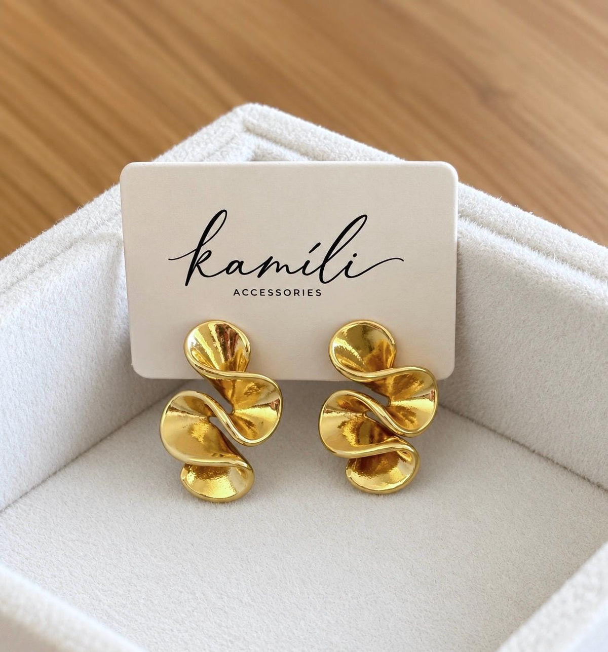 Pair of gold-tone abstract swirl stud earrings on Kamili Accessories jewellery display card