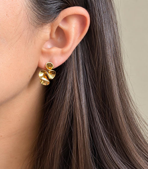 Gold-plated sculptural swirl statement stud earring worn on the ear