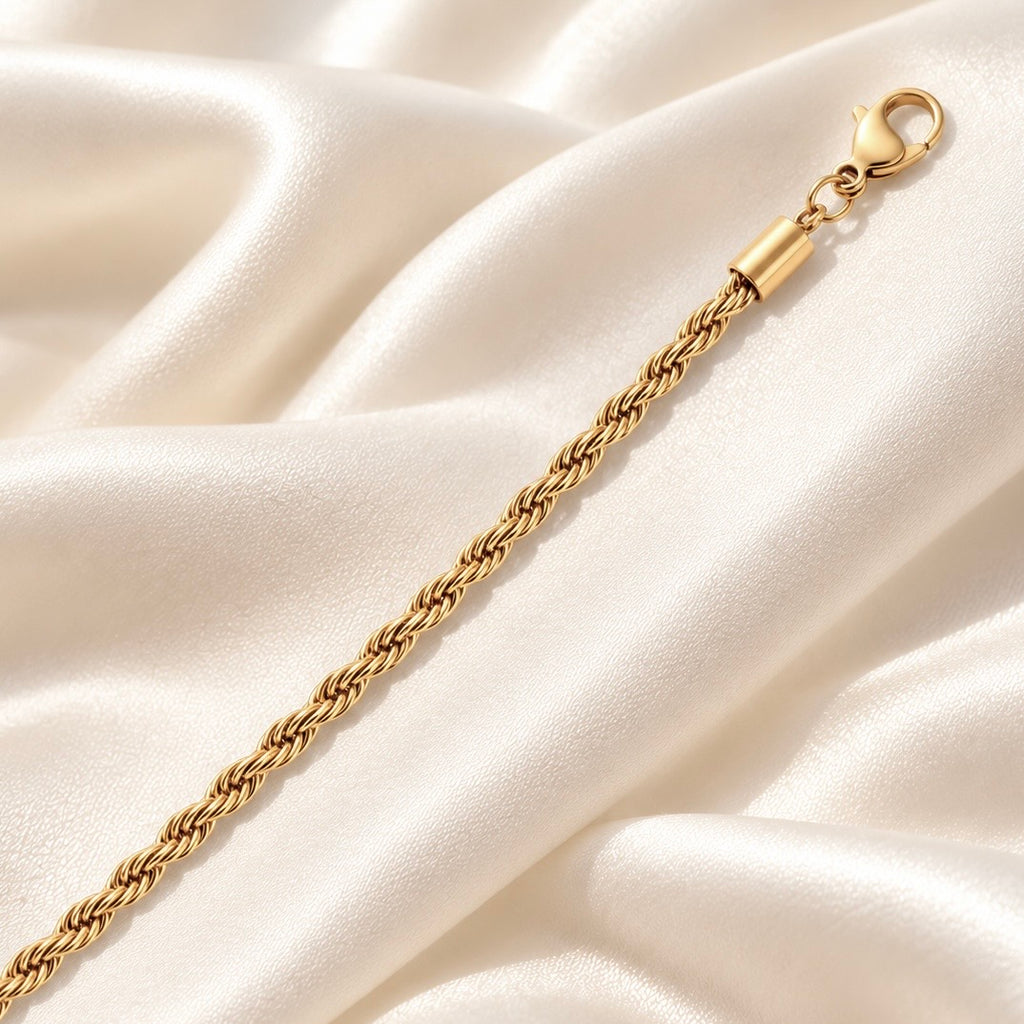Detail of gold rope chain bracelet with lobster clasp on satin
