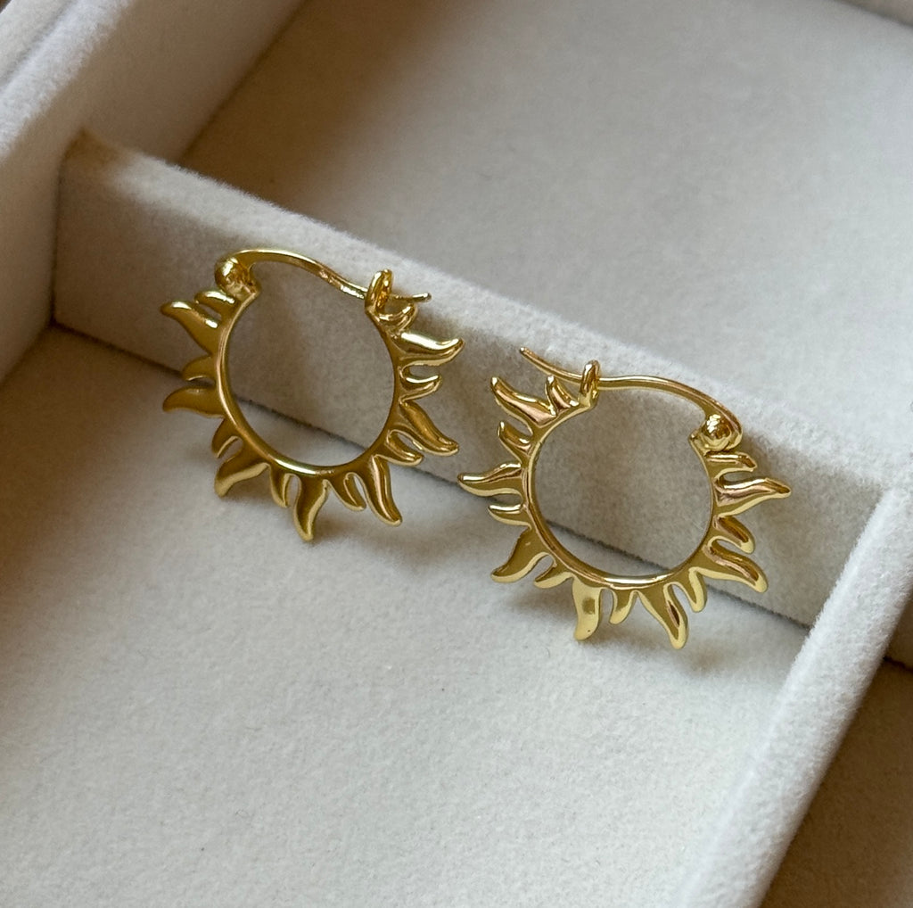 Detailed view of gold sunburst celestial hoop earrings