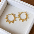 Pair of gold plated sunray hoop earrings on ivory velvet