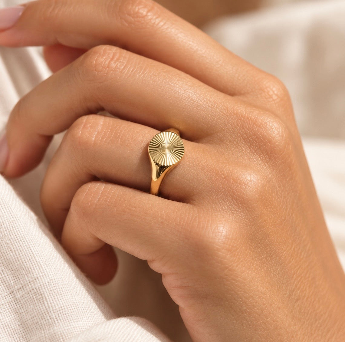 Detailed photograph of the golden textured sunburst signet face on a hand
