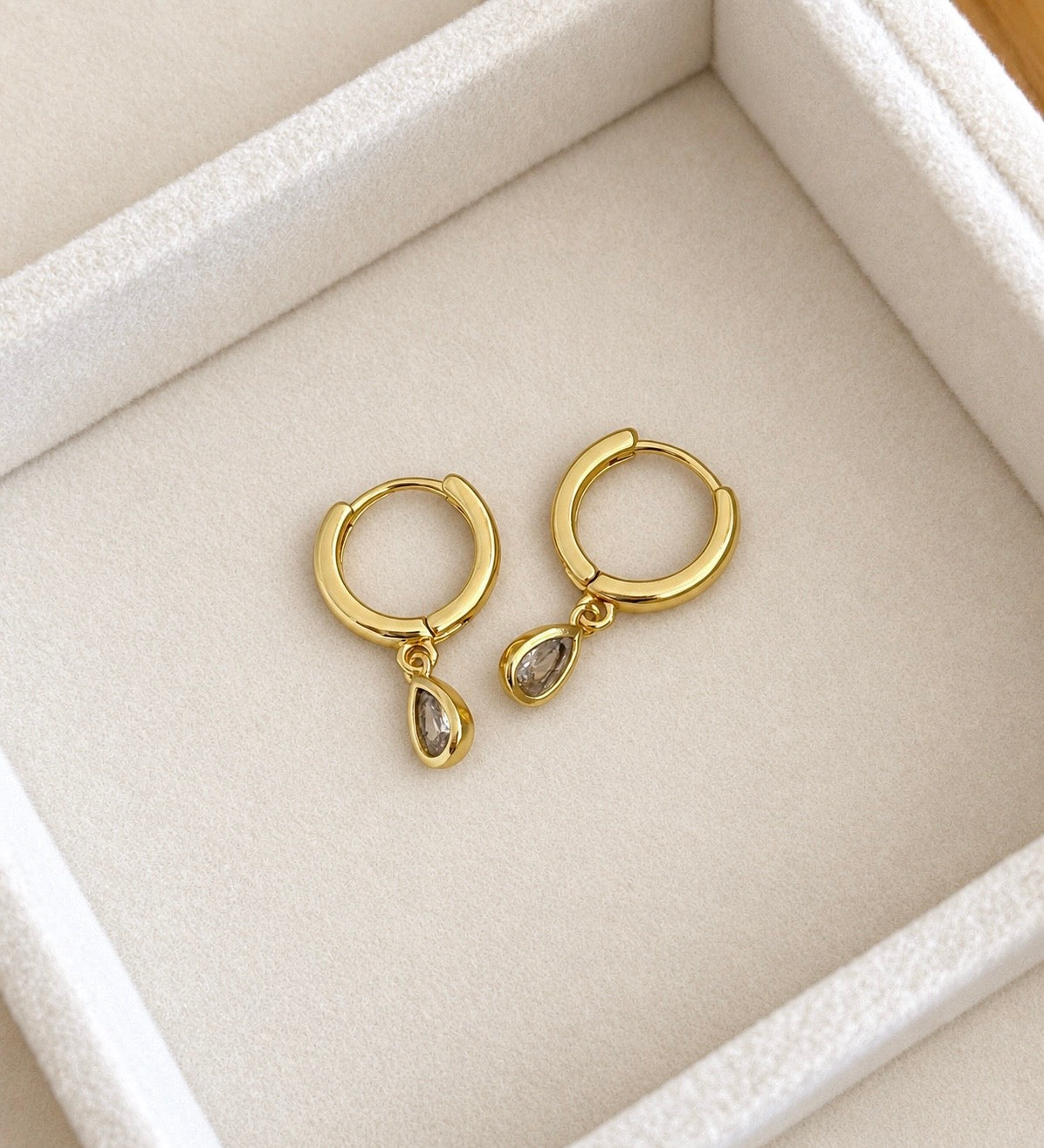 Angled side view of gold teardrop CZ hoop earrings