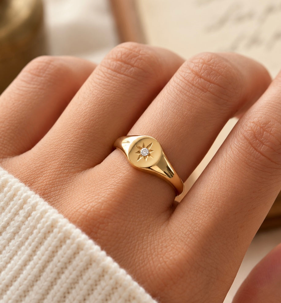 Starburst signet ring shown styled on hand with white knitted sleeve
