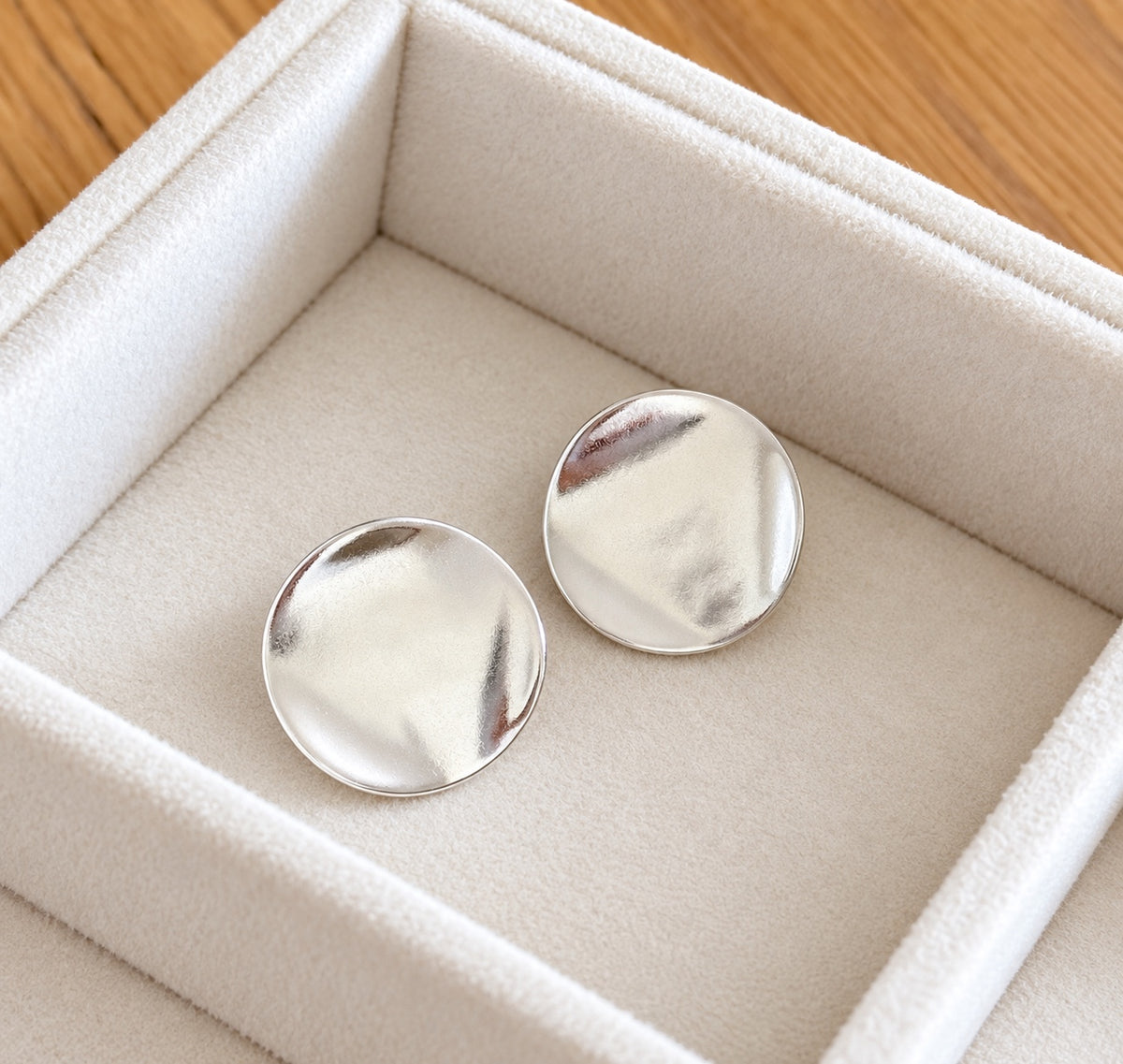 Pair of polished silver organic disc stud earrings in an ivory jewellery box