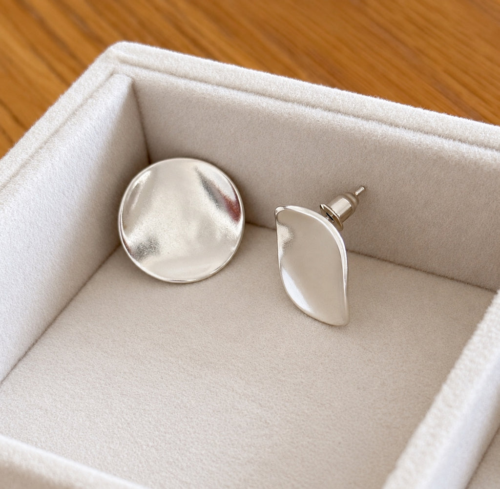 Side view of silver organic disc stud earrings showing post
