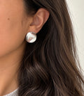 Sculptural silver disc stud earring worn on ear