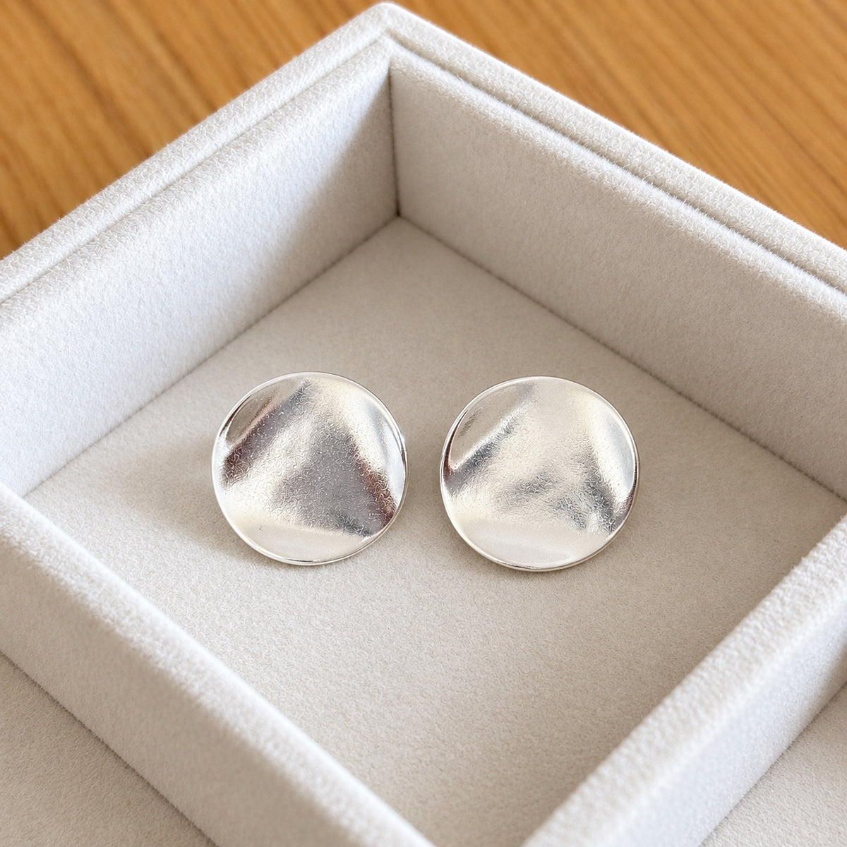 Close-up of polished organic silver disc earrings