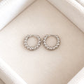 Pair of petite sterling silver beaded huggie hoop earrings on cream velvet