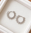 Pair of 925 sterling silver beaded sunburst hoop earrings on an ivory jewellery tray