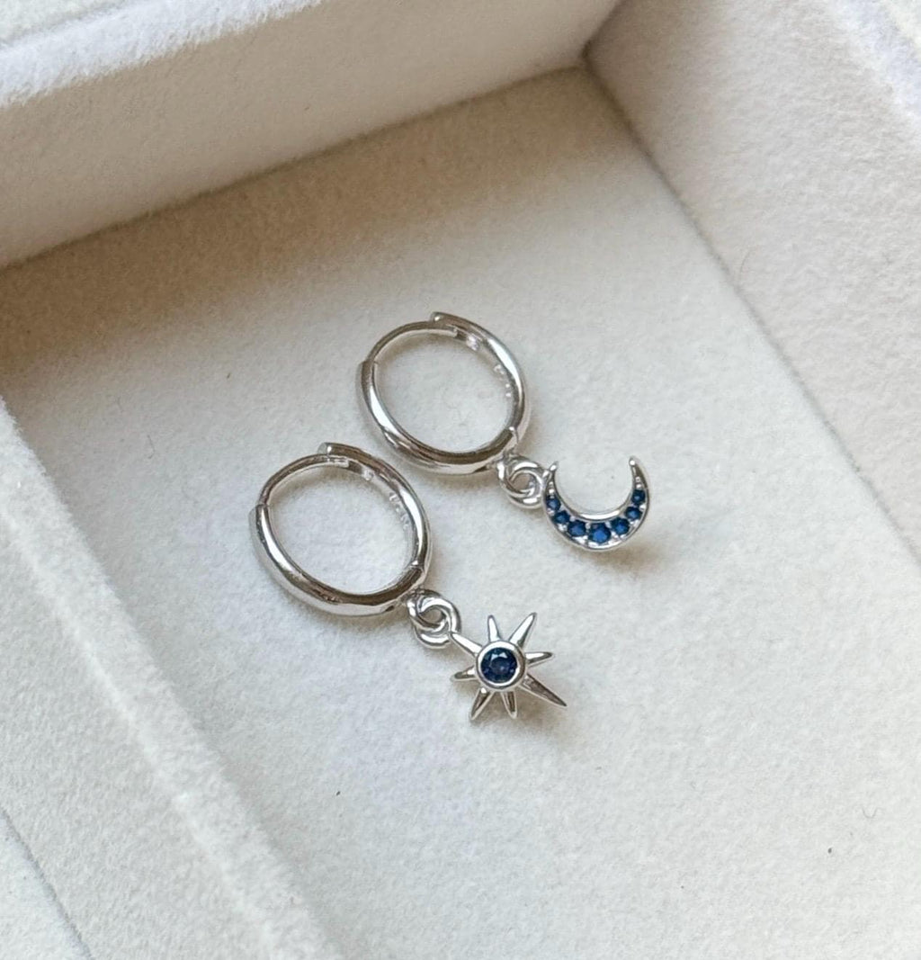 Pair of silver hoop earrings with matching dark blue CZ moon and star charms