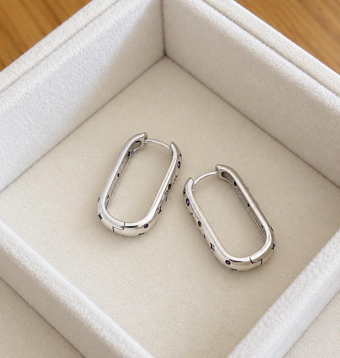 Rear and side view of polished silver elongated hoop earrings displaying hinged click closures