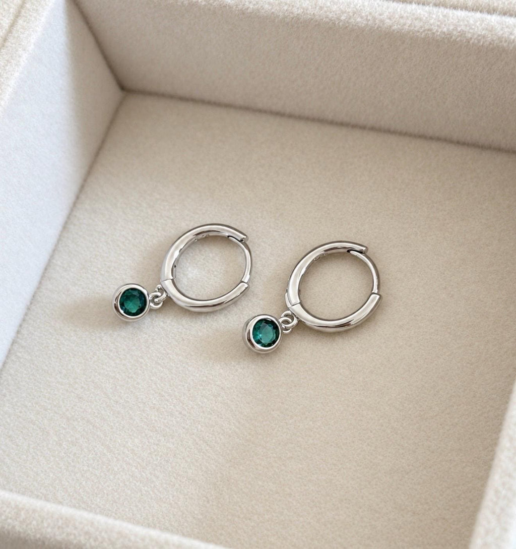 Silver colour huggie hoop earrings with dangling green CZ round stones