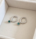 Silver colour huggie hoop earrings with dangling green CZ round stones