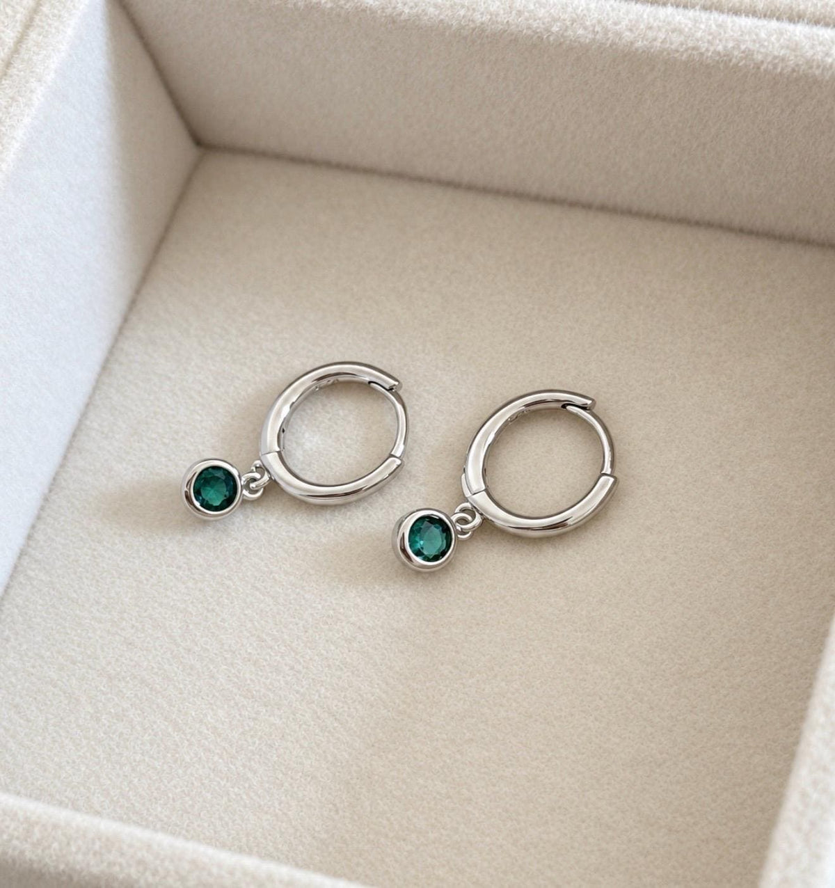 Silver colour huggie hoop earrings with dangling green CZ round stones